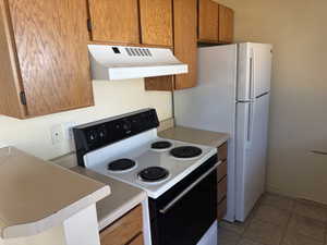 Kitchen featuring wood-finish cabinetry, a white electric range with a hood vent, and a white side-by-side refrigerator