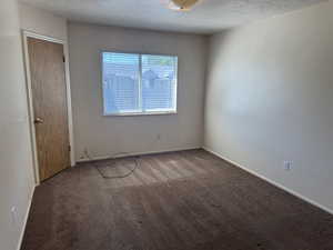 Carpeted room with a window featuring horizontal blinds, a wood-finish door, and neutral wall tones