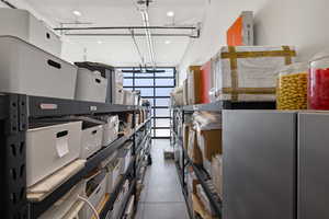 Dedicated storage area featuring industrial shelving units, polished concrete flooring, recessed lighting, and a full-view garage door
