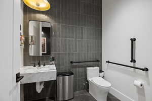 Contemporary bathroom featuring a floating white marble vanity with integrated sink, black fixtures, a rectangular mirror, and gray subway tile accent wall