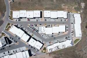Aerial view of a commercial complex featuring multiple buildings with white flat roofs and integrated parking areas