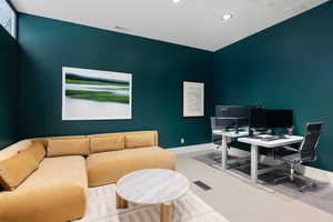 Spacious room featuring deep teal walls, recessed lighting, high ceilings, and light-colored carpeting