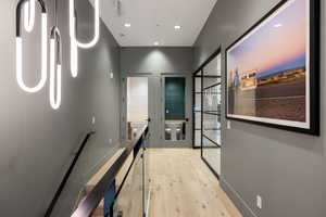 Hallway featuring light wood-finish flooring, recessed lighting, and a contemporary pendant light fixture