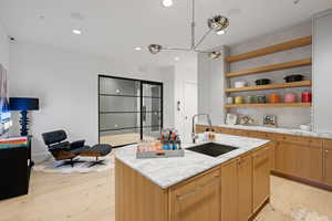 Kitchen island with a white marble countertop and integrated sink, complemented by light wood-finish cabinetry