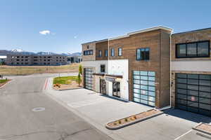 Modern commercial building featuring wood-finish siding, stone accents, and large glass garage doors