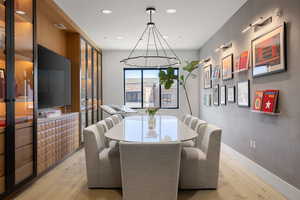 Dining area featuring wood-finish flooring, a contemporary chandelier, and a large window