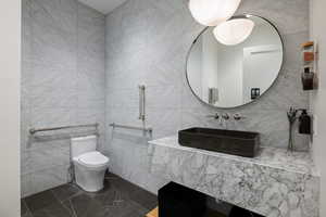 Modern washroom featuring full-height light marble-patterned wall tiles and dark floor tiles