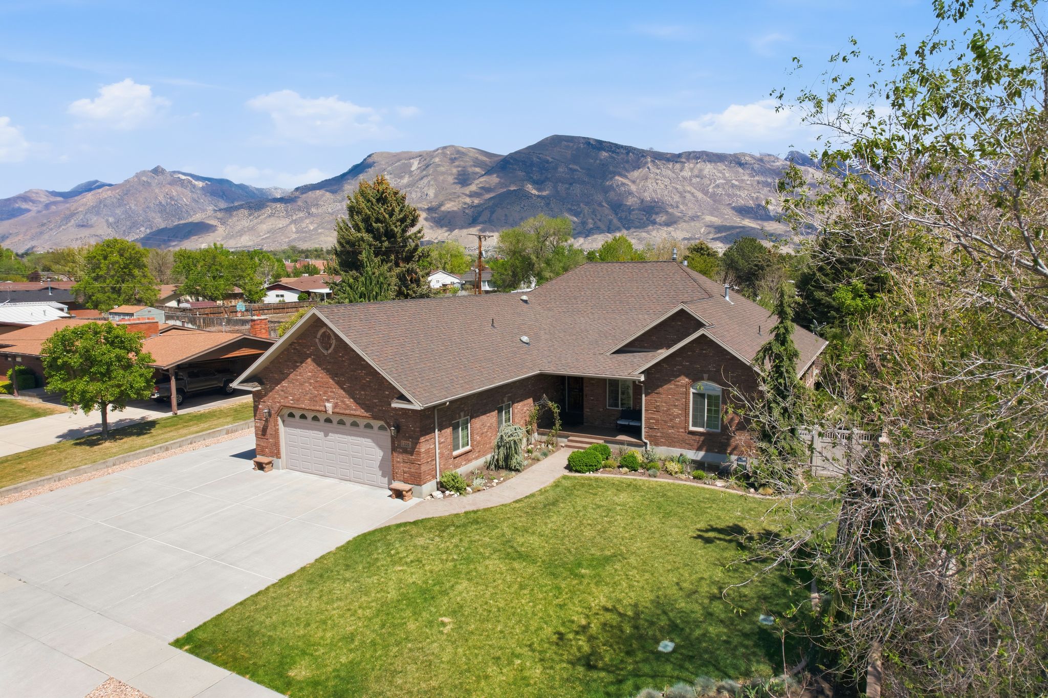 View of front of house with brick siding, roof with shingles, concrete driveway, an attached garage, and a front yard
