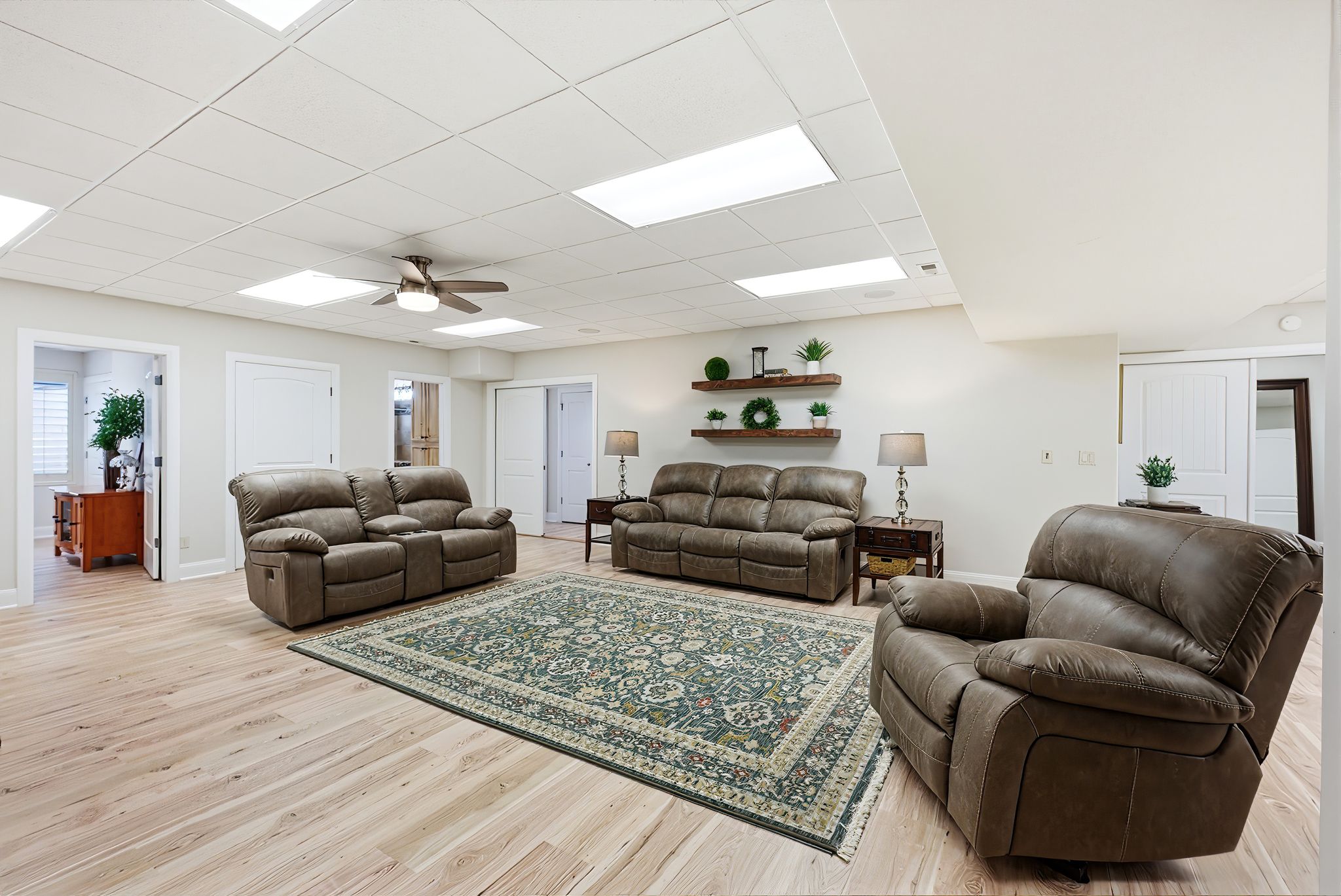 Living room featuring light wood-style flooring, a paneled ceiling, and ceiling fan
