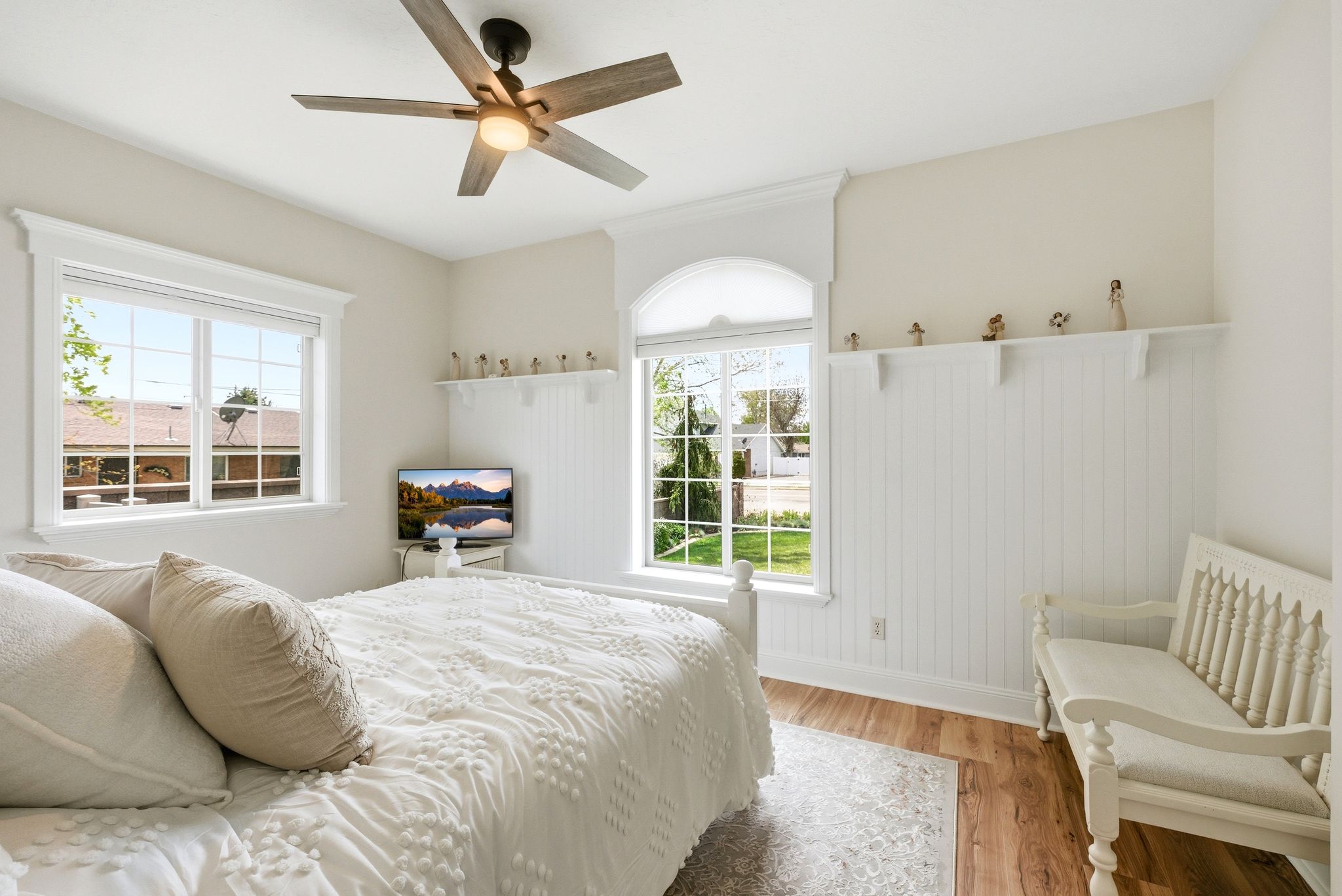 Bedroom with wood finished floors, ceiling fan, and wainscoting