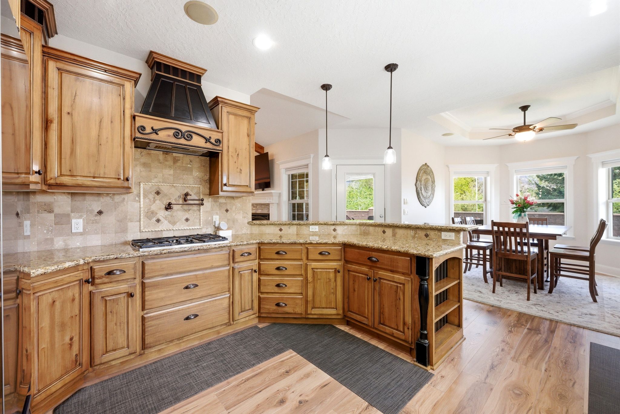 Kitchen featuring light wood-style floors, a tray ceiling, light stone countertops, open shelves, and ceiling fan