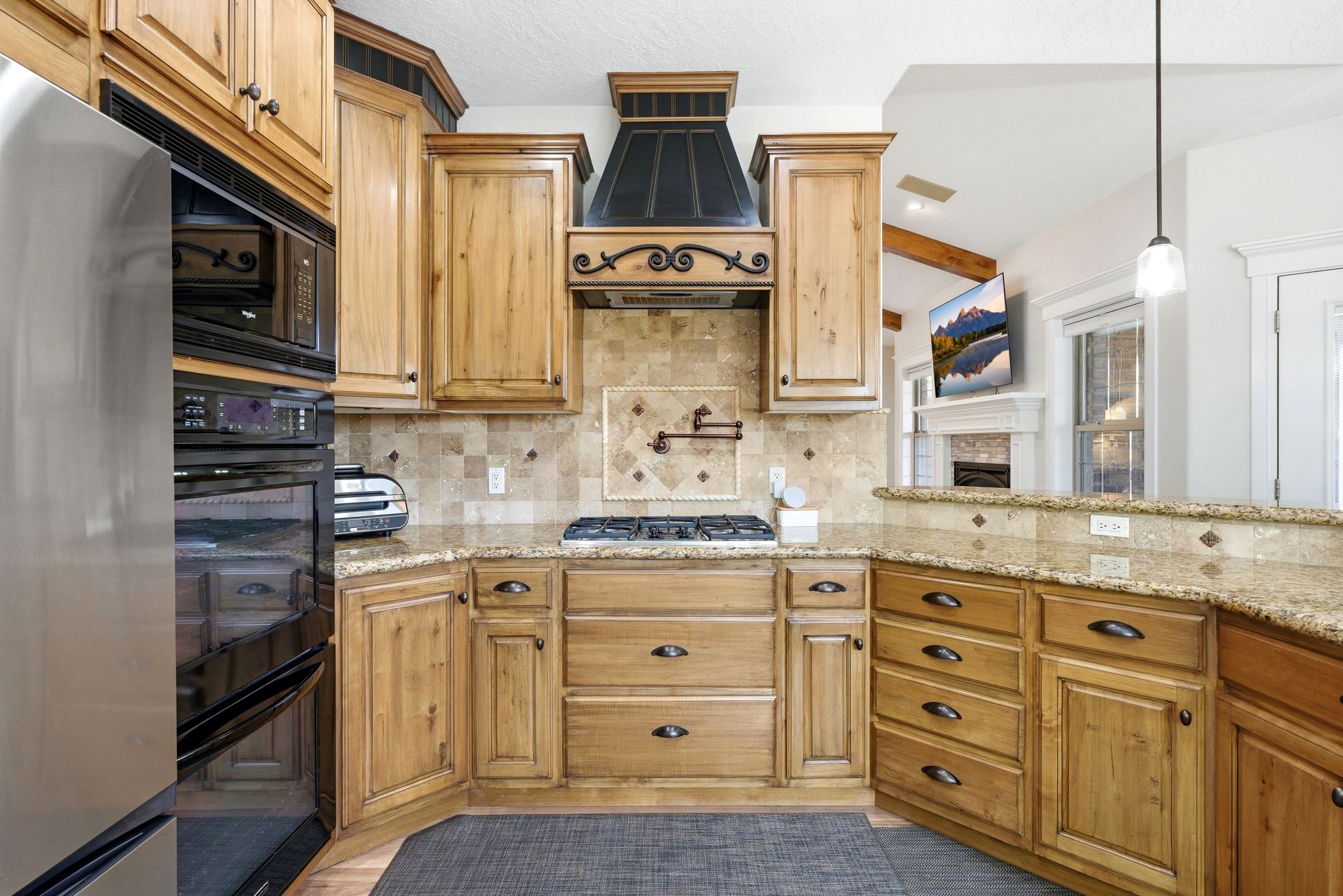 Kitchen with black appliances, pendant lighting, light stone counters, and tasteful backsplash