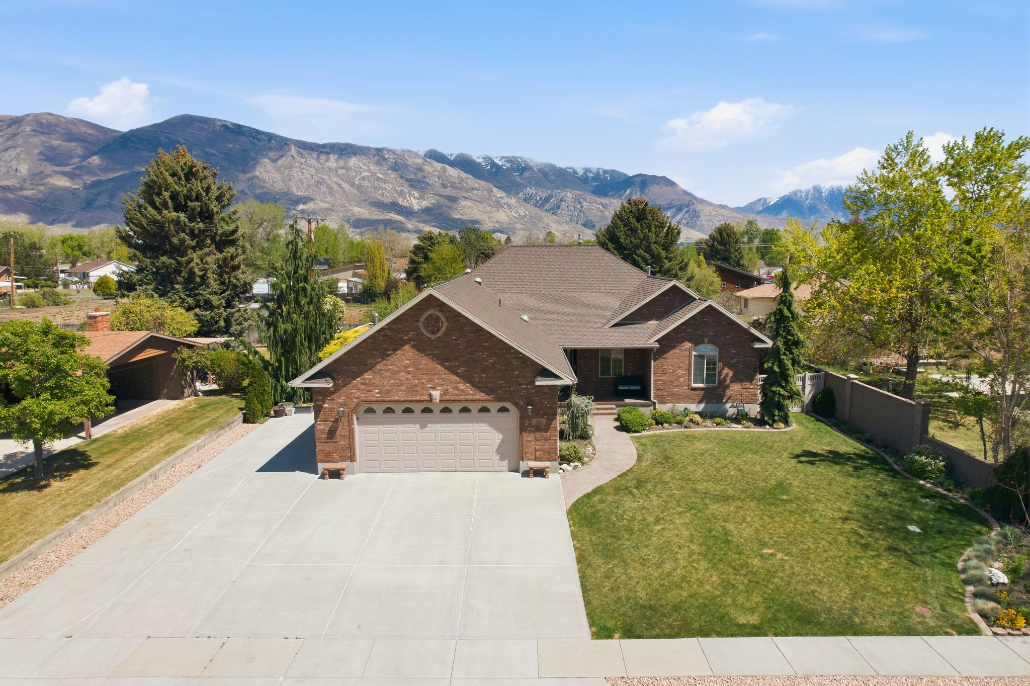 View of front of property with brick siding, a garage, driveway, and a mountain view