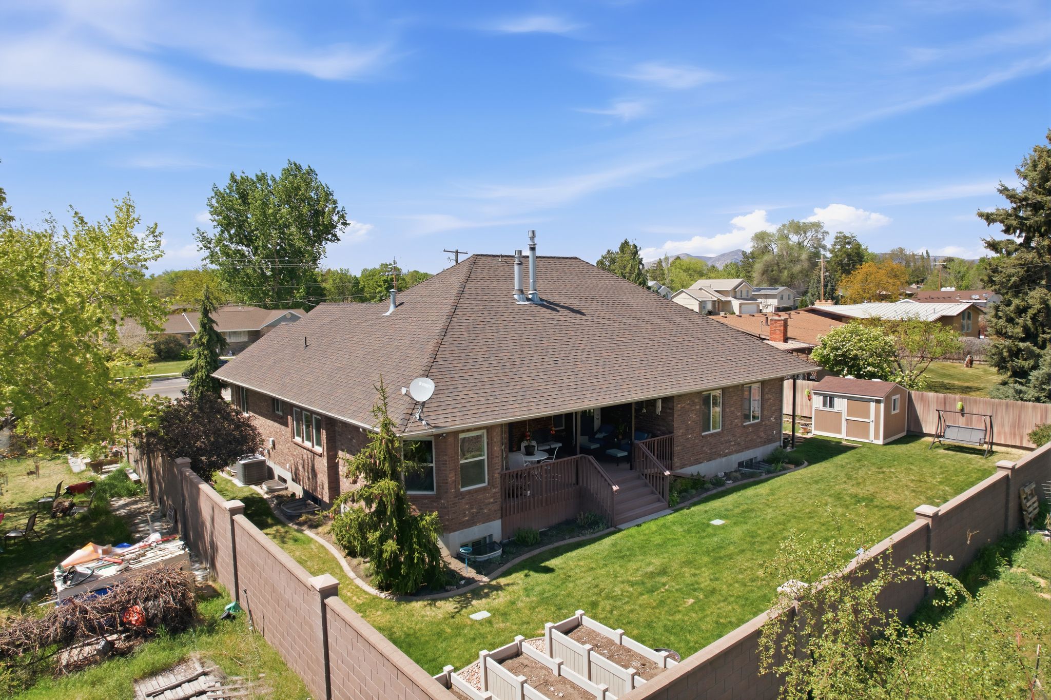 Back of property with a storage unit, a fenced backyard, a deck, and brick siding