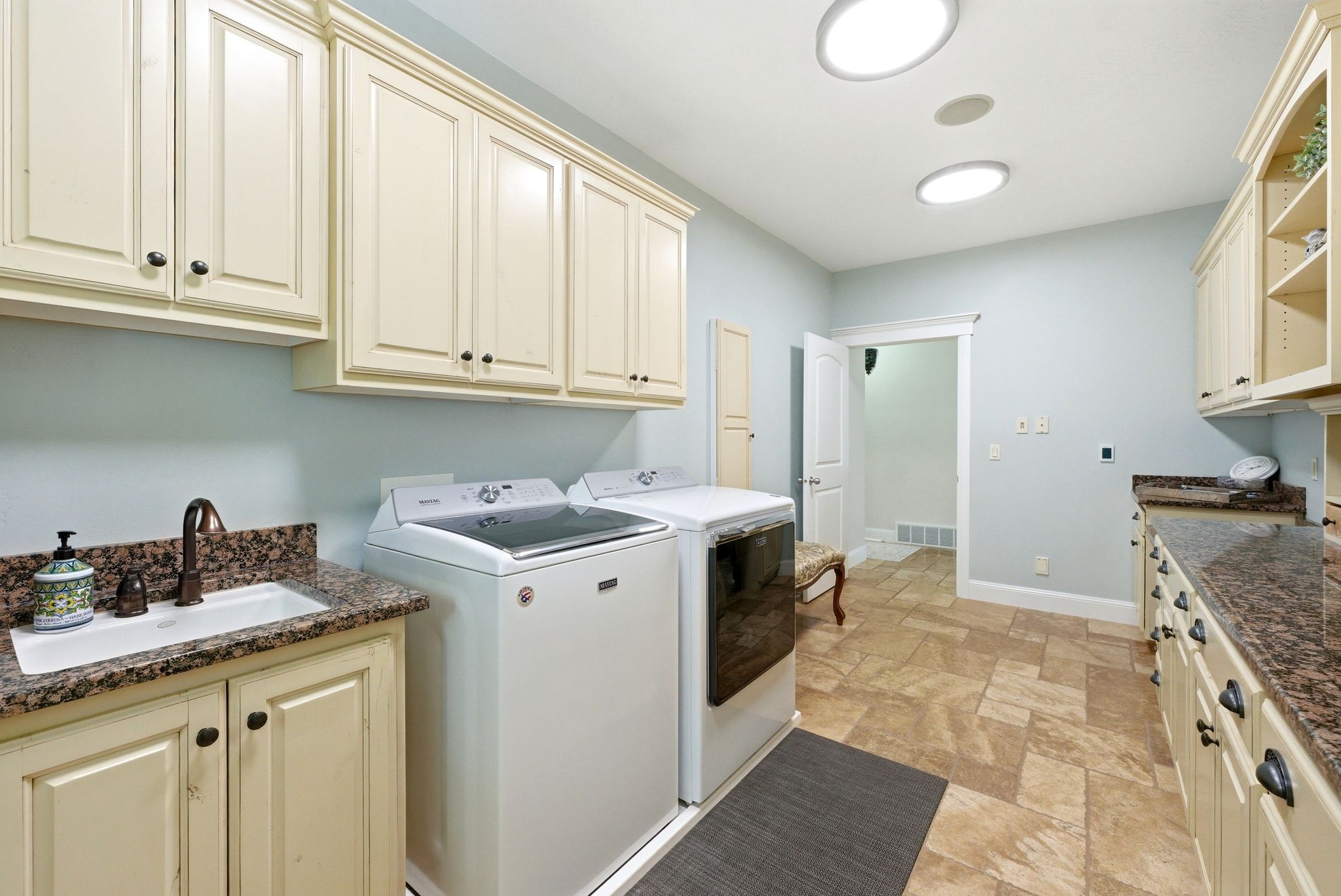 Laundry room with cabinet space and light stone finish flooring