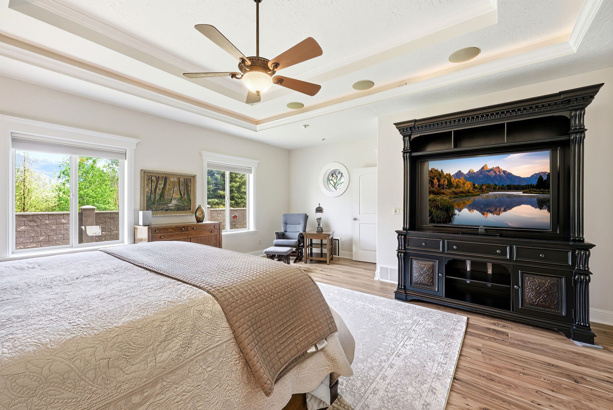 Bedroom featuring light wood-type flooring, ceiling fan, and a tray ceiling