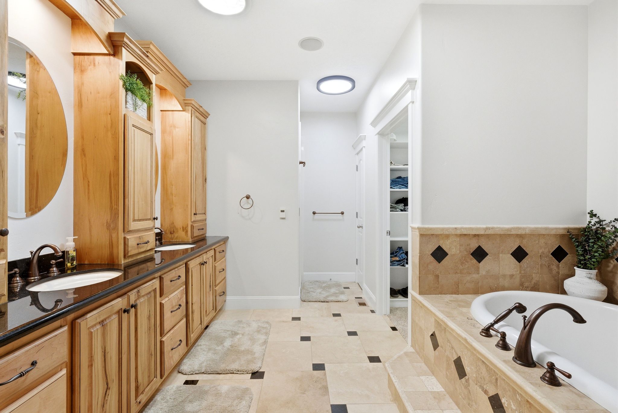 Bathroom with double vanity, a garden tub, light tile patterned flooring, and a spacious closet