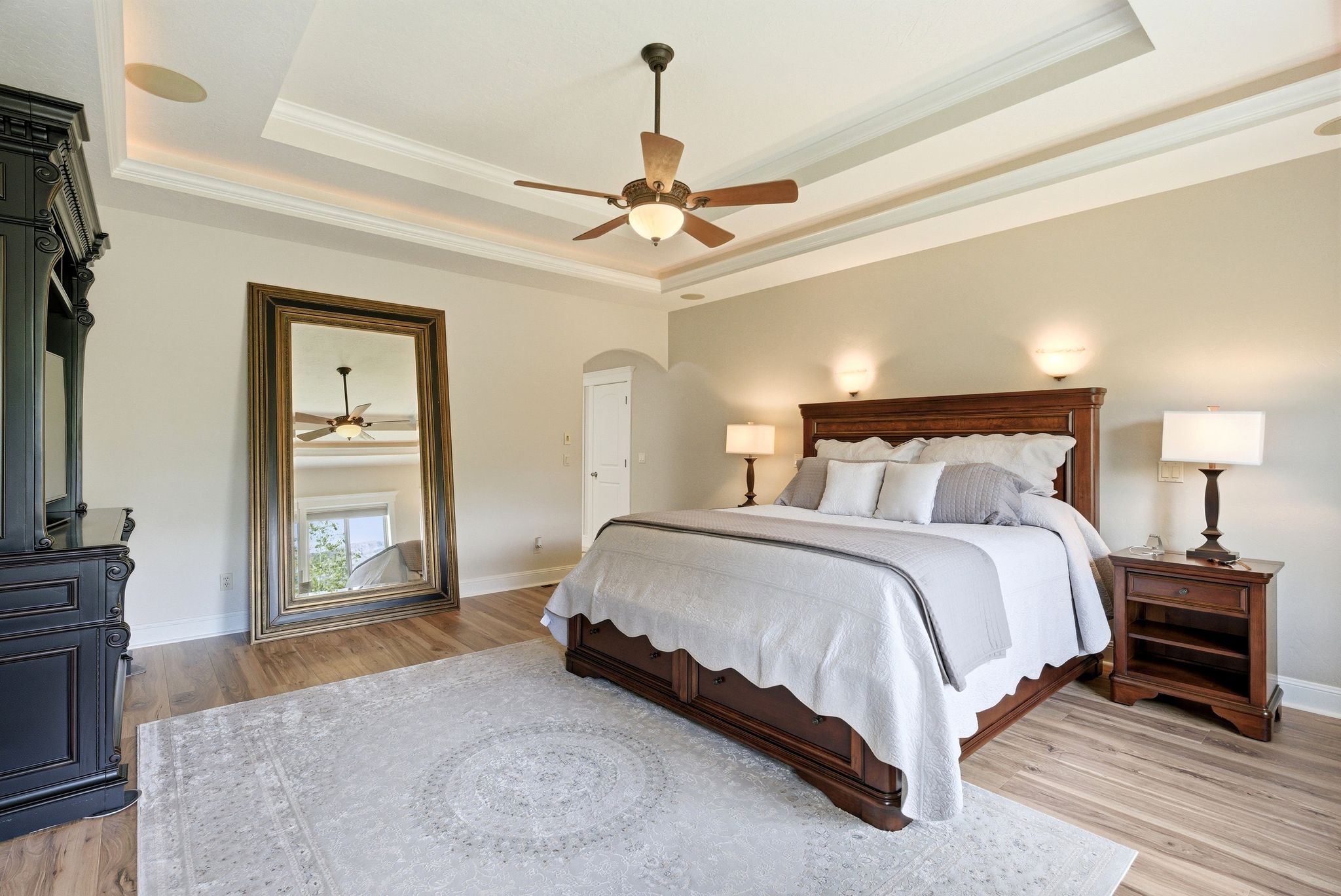 Bedroom with ornamental molding, light wood-style flooring, a ceiling fan, and arched walkways