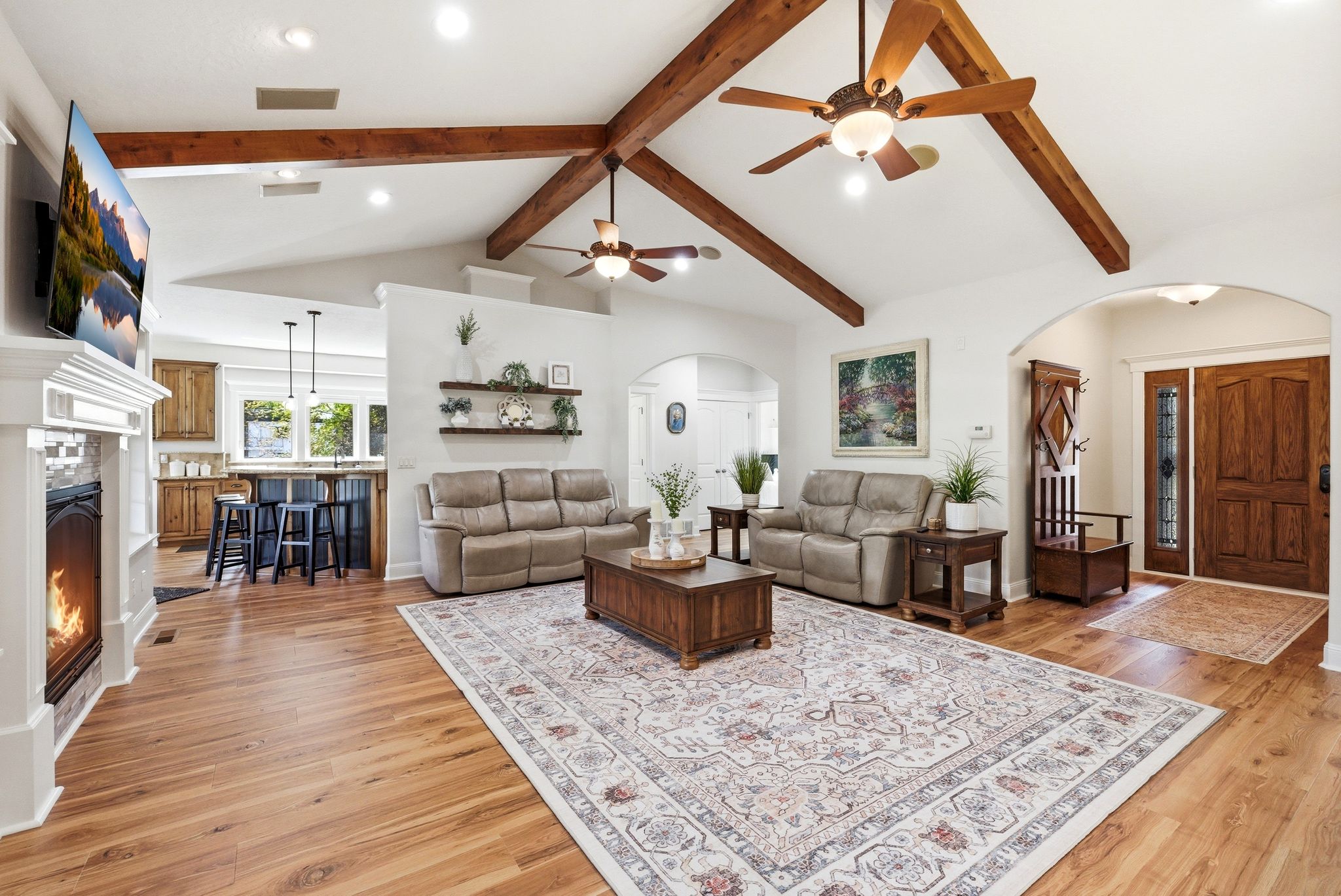 Living area featuring a warm lit fireplace, arched walkways, recessed lighting, light wood-style flooring, and a ceiling fan