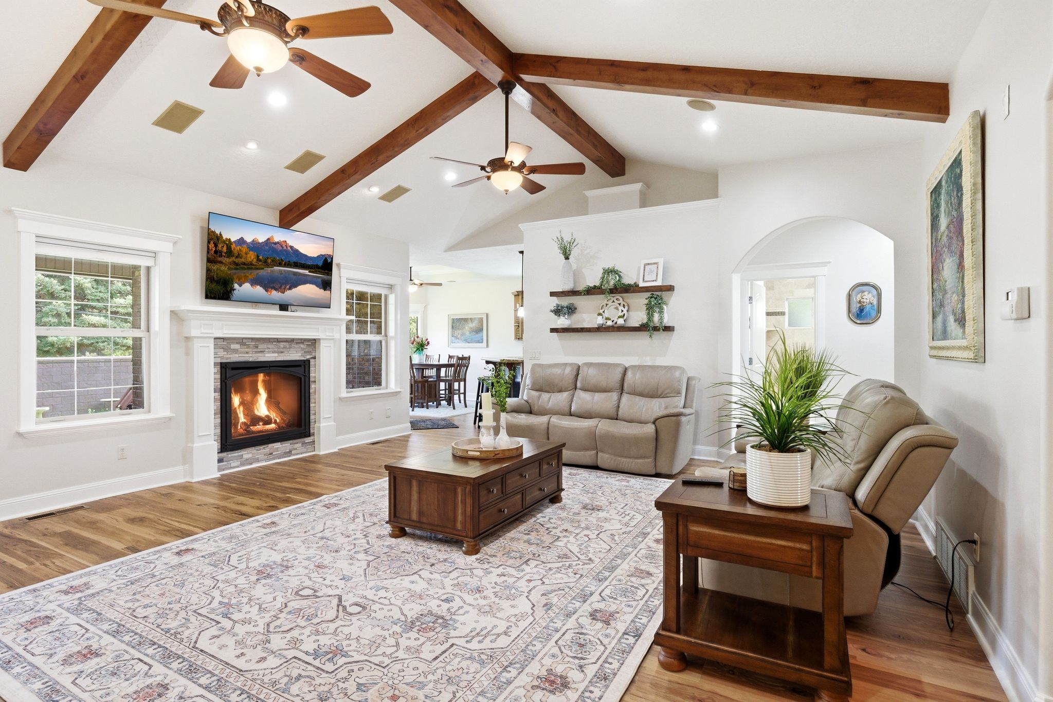 Living area with light wood finished floors, ceiling fan, a stone fireplace, and recessed lighting