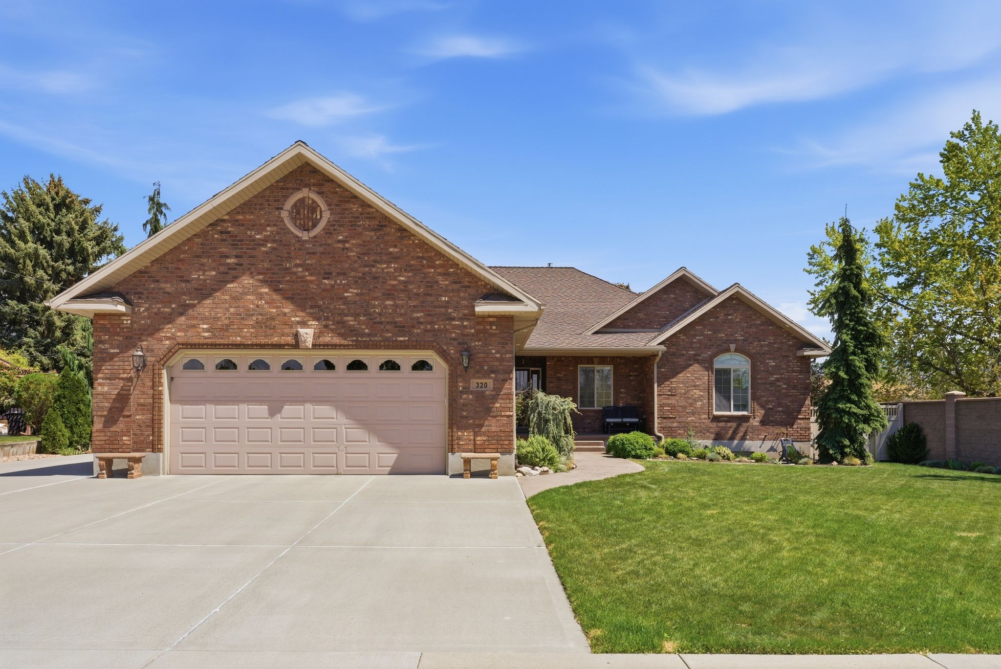 Single story home featuring an attached garage, a front lawn, concrete driveway, and brick siding