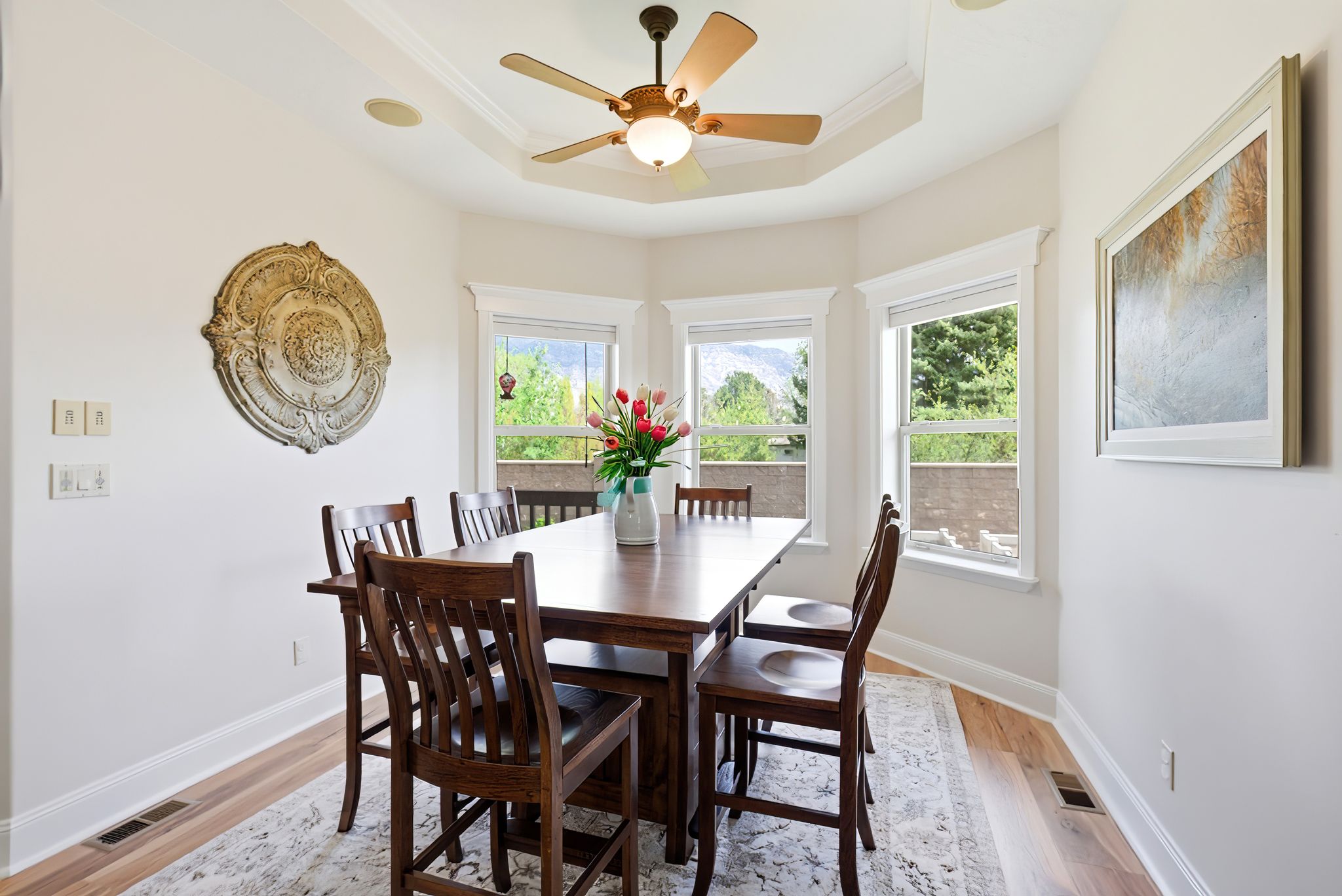 Dining area with light wood finished floors, healthy amount of natural light, ceiling fan, and crown molding
