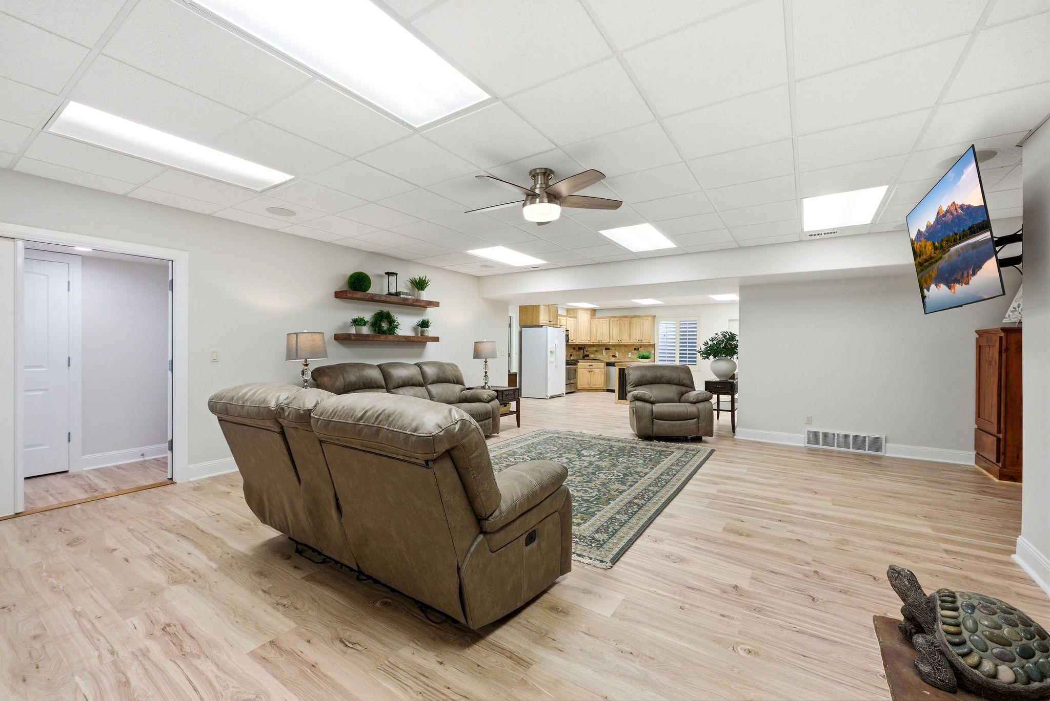 Living room with light wood finished floors, a ceiling fan, and a paneled ceiling
