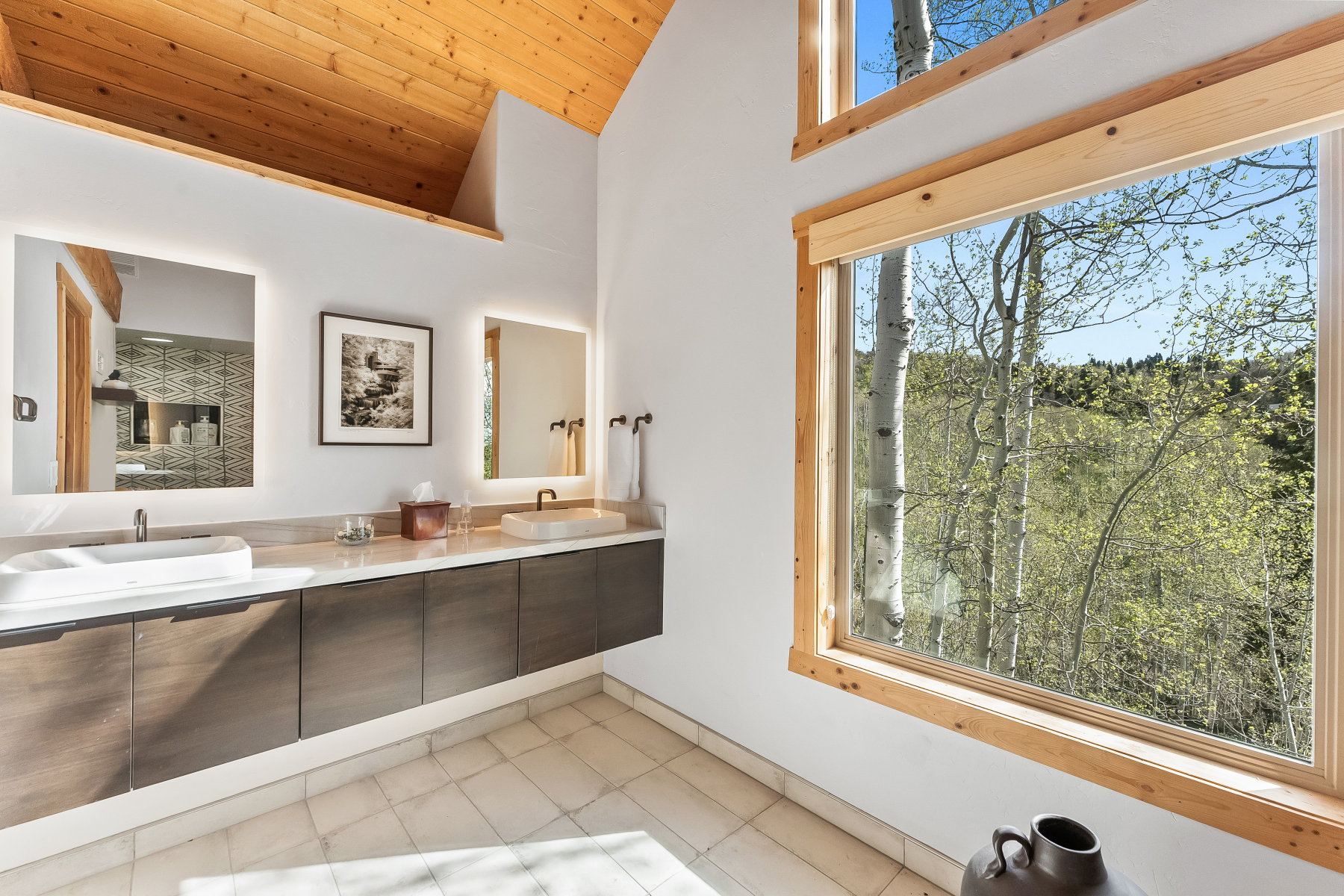 Vaulted wood-plank ceiling accenting a bathroom with a floating dual vanity, vessel sinks, and integrated mirror lighting