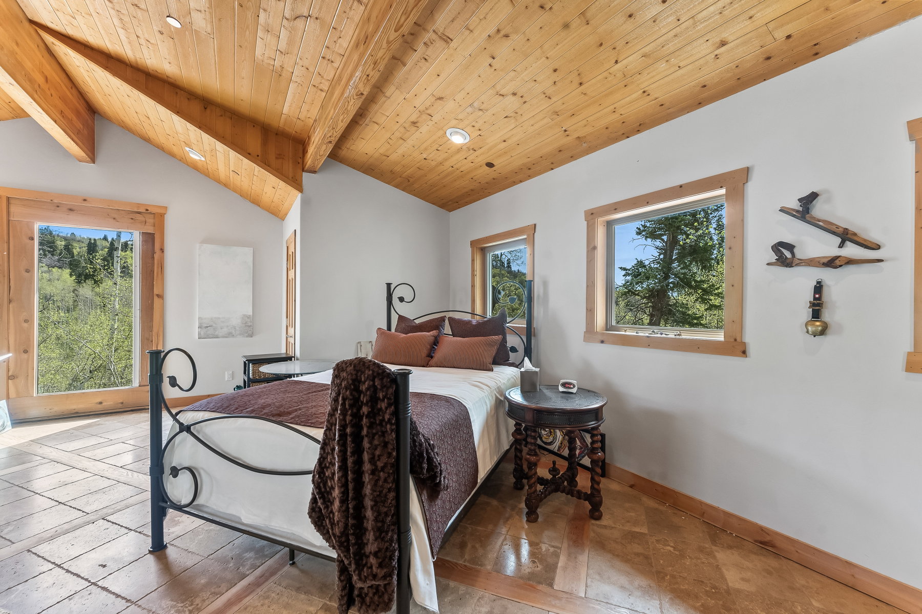 Vaulted wood-plank ceiling with exposed beams, recessed lighting, wood-trimmed windows, and tile flooring