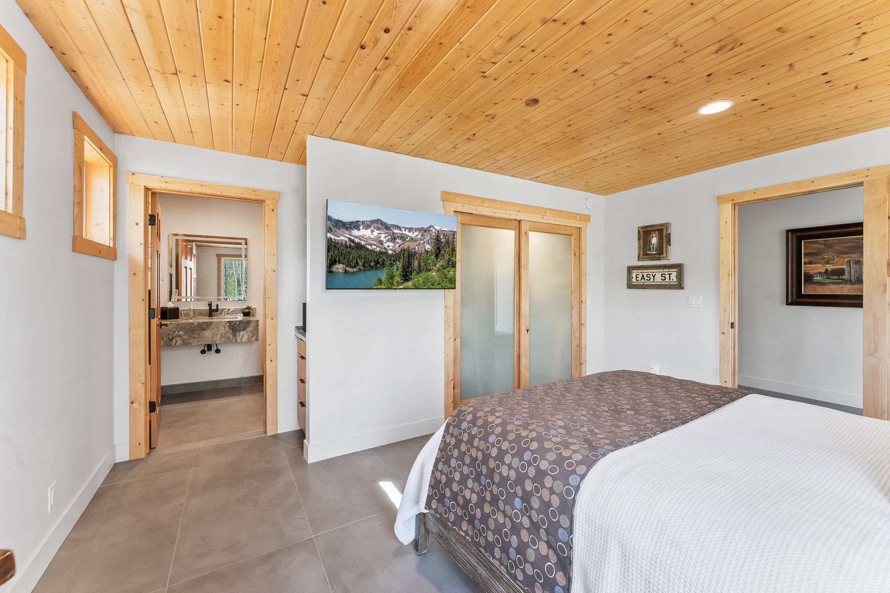 Bedroom featuring a wood-finish plank ceiling, two window openings with wood-finish trim, and large format floor tiling