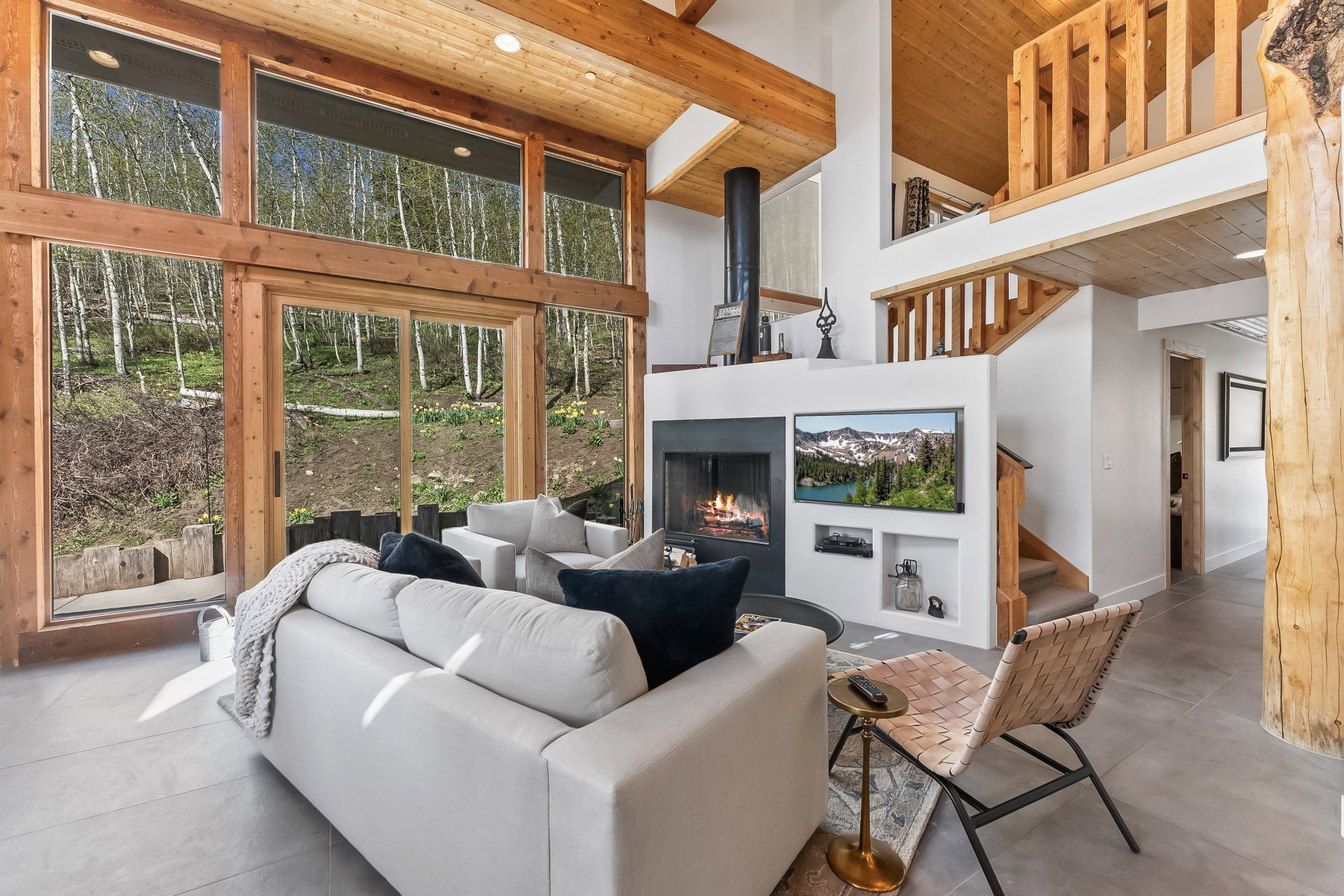 Great room featuring a vaulted ceiling with exposed wood beams, a floor-to-ceiling fireplace with built-in shelving, and large windows with sliding glass doors