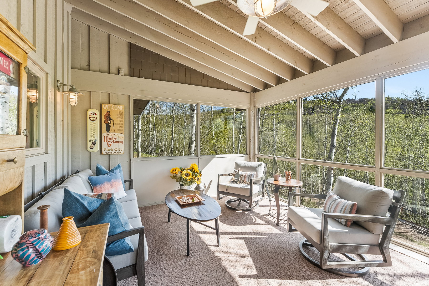 Screened porch featuring exposed beam ceiling, wall-mounted light fixture, and carpeted flooring