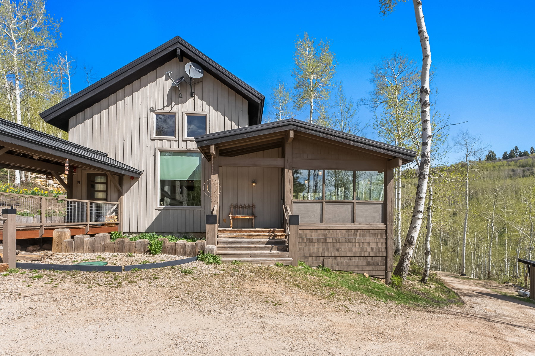 Rustic-inspired architecture featuring vertical wood siding, a covered porch with shingle detailing, and a multi-level deck with metal railings