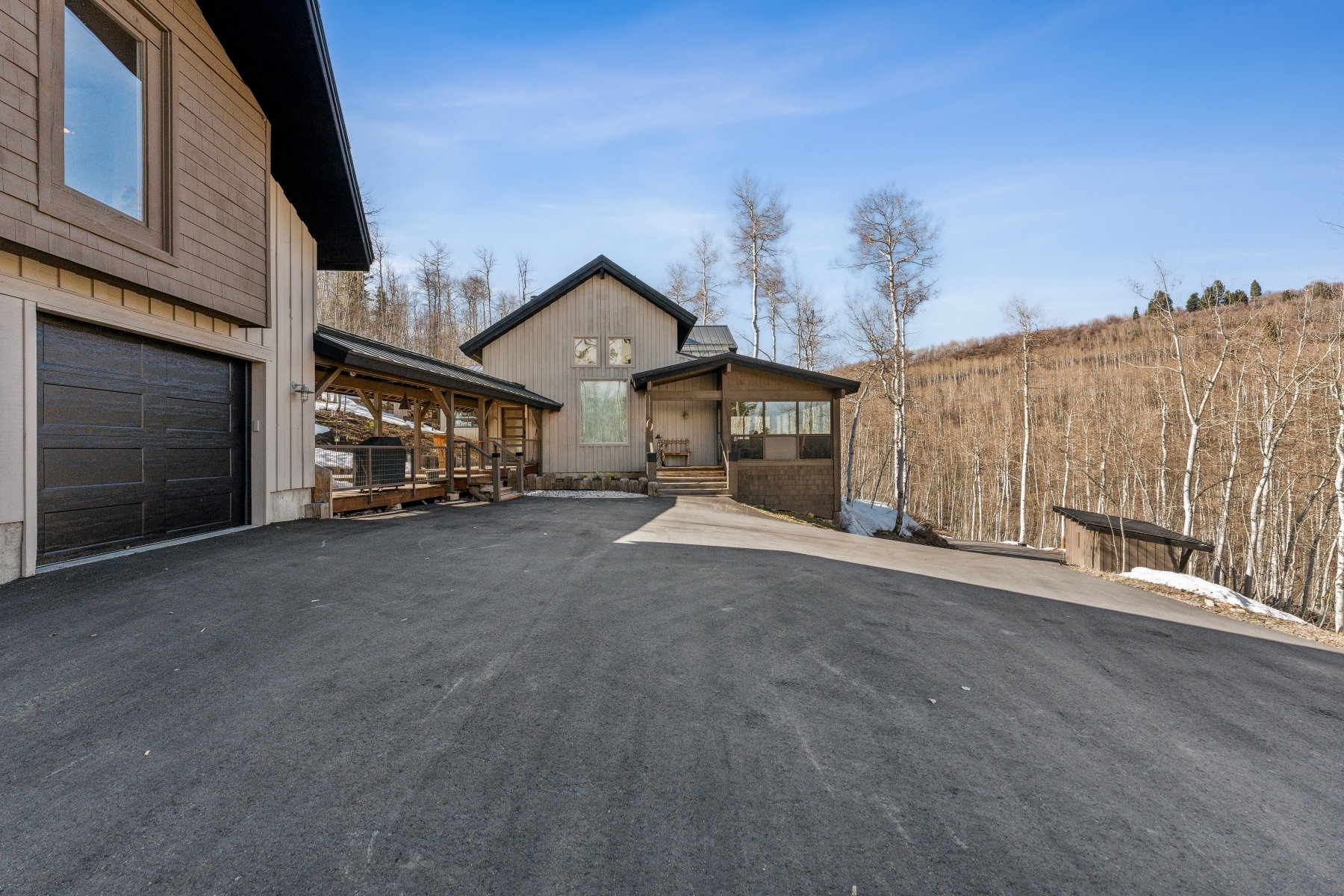 Asphalt driveway leading to a multi-level residence with a prominent attached garage
