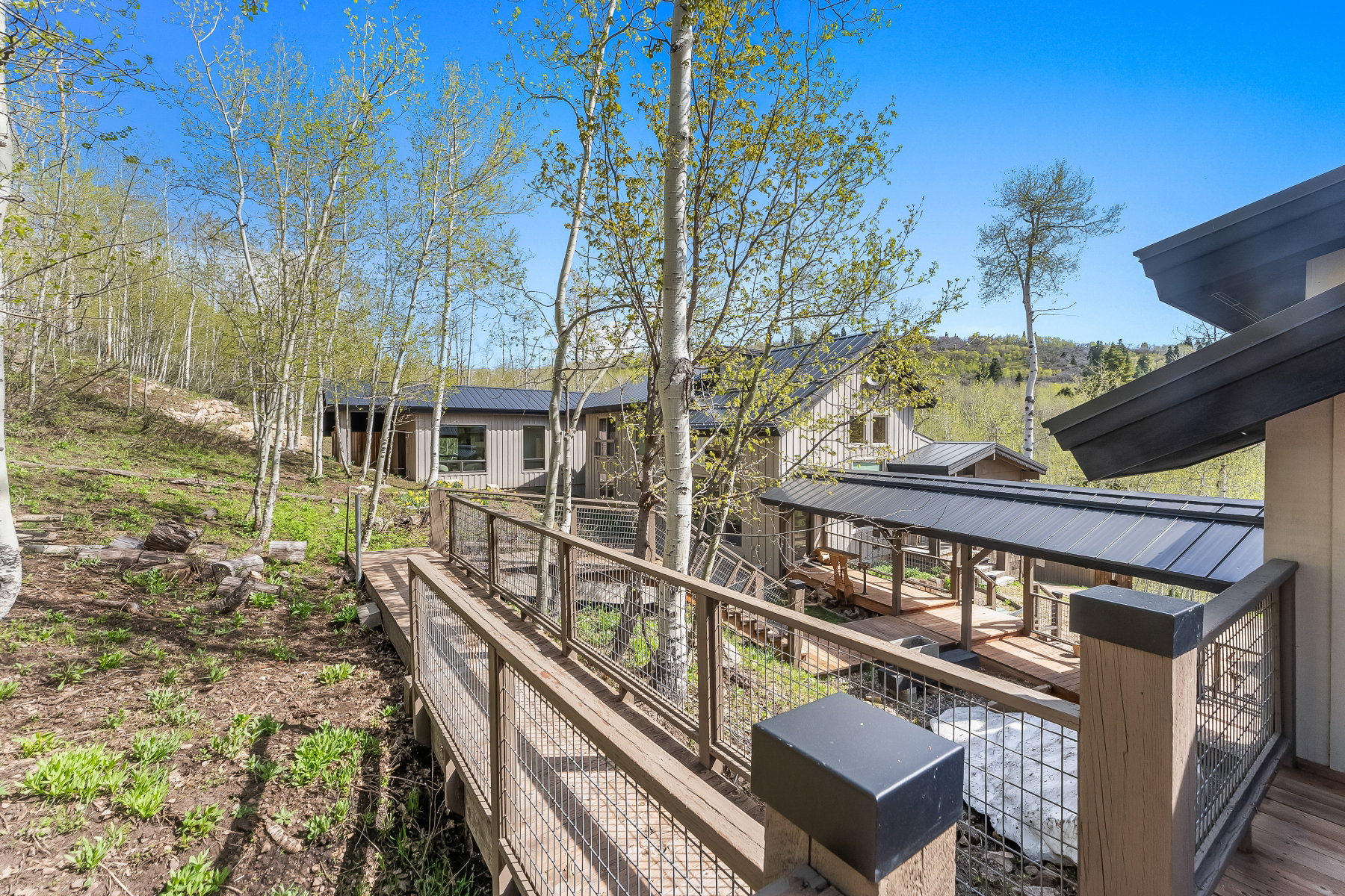 Wood-plank walkway with cable railings extending towards the property
