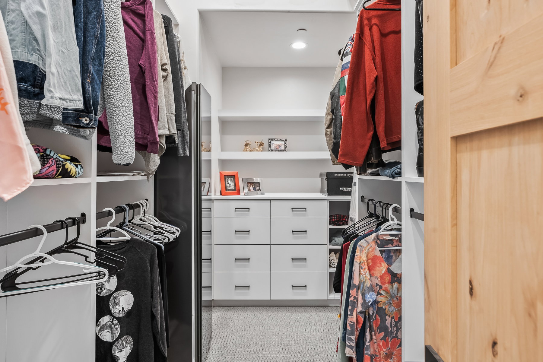 Custom closet system featuring built-in white cabinetry, integrated shelving, and multiple hanging rods