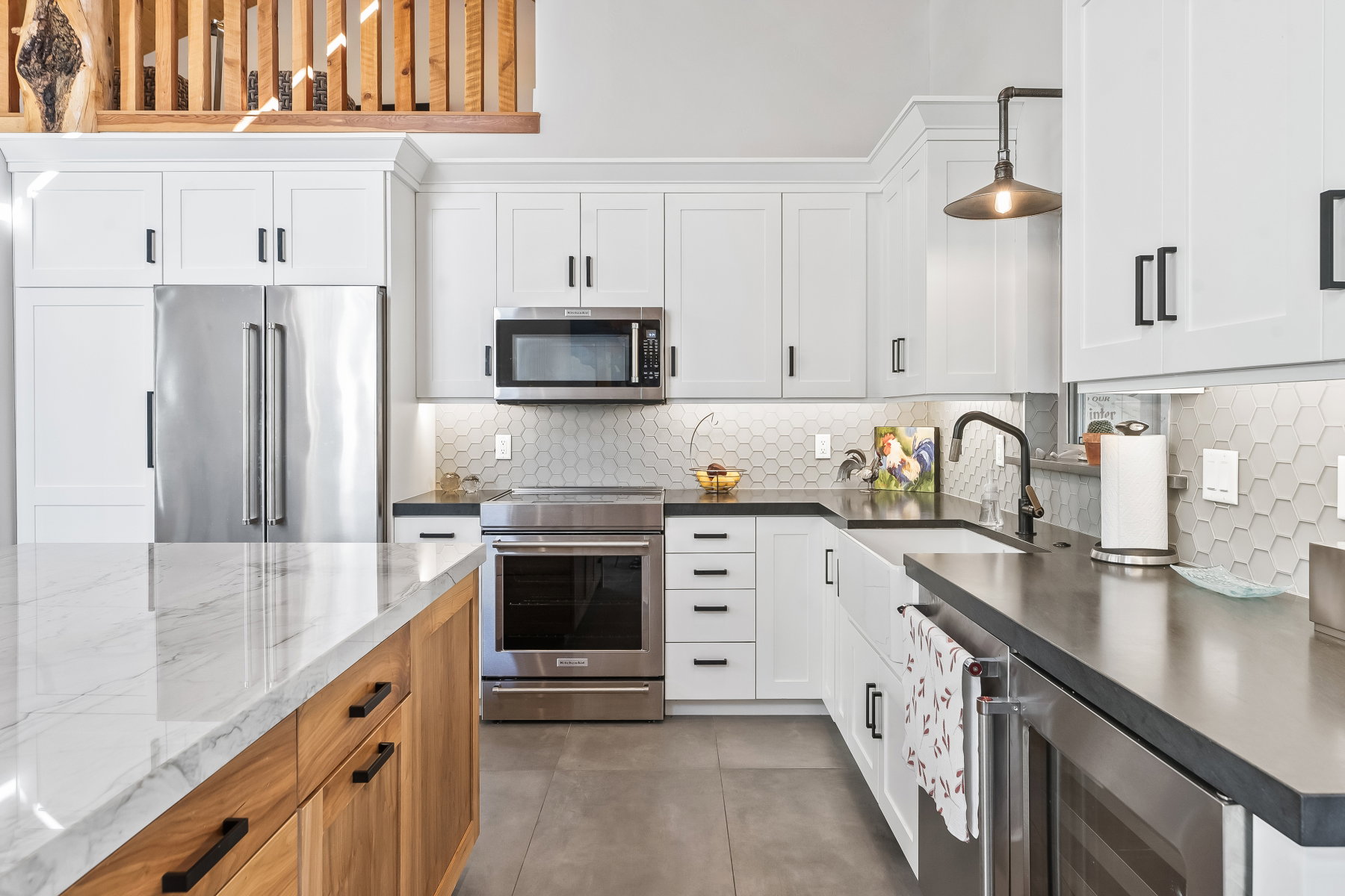Modern kitchen featuring white shaker cabinetry and a light wood-finish island with a stone countertop