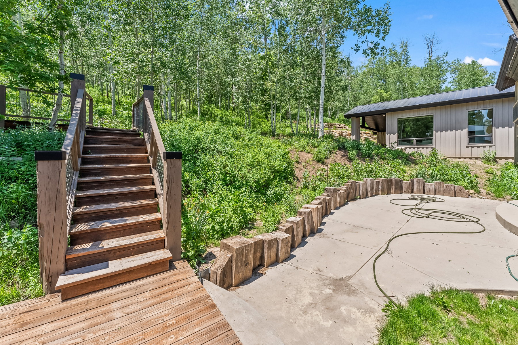 Exterior wood deck and staircase leading to an elevated wooded area