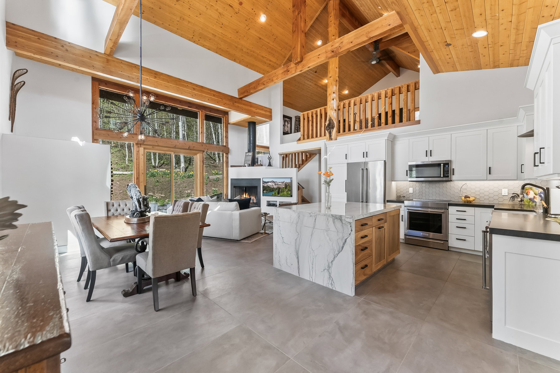 Open-concept living space with vaulted wood-plank ceilings and exposed beams