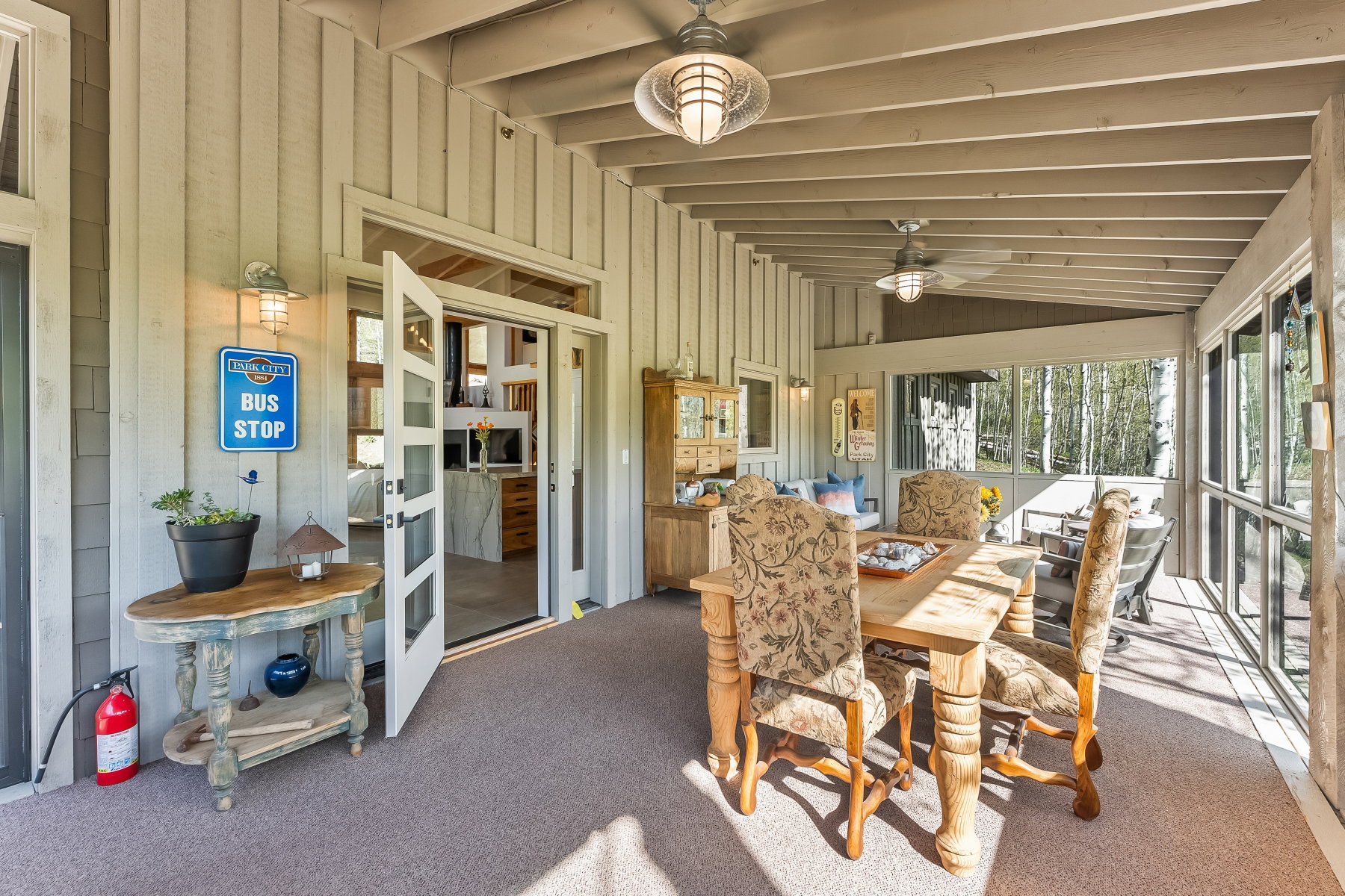 Screened-in patio with exposed beam ceiling, ceiling fans, and an exterior wall featuring vertical siding