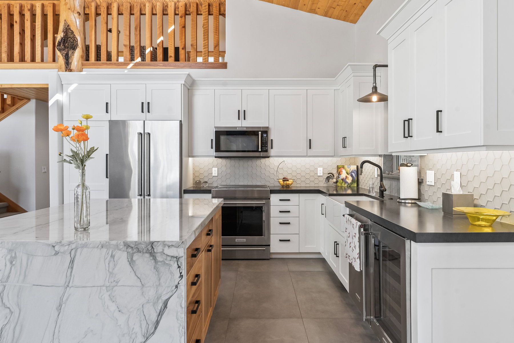 Gourmet kitchen featuring a waterfall island with a stone countertop, white shaker cabinetry, stainless steel appliances, a hexagonal tile backsplash, and a beverage refrigerator