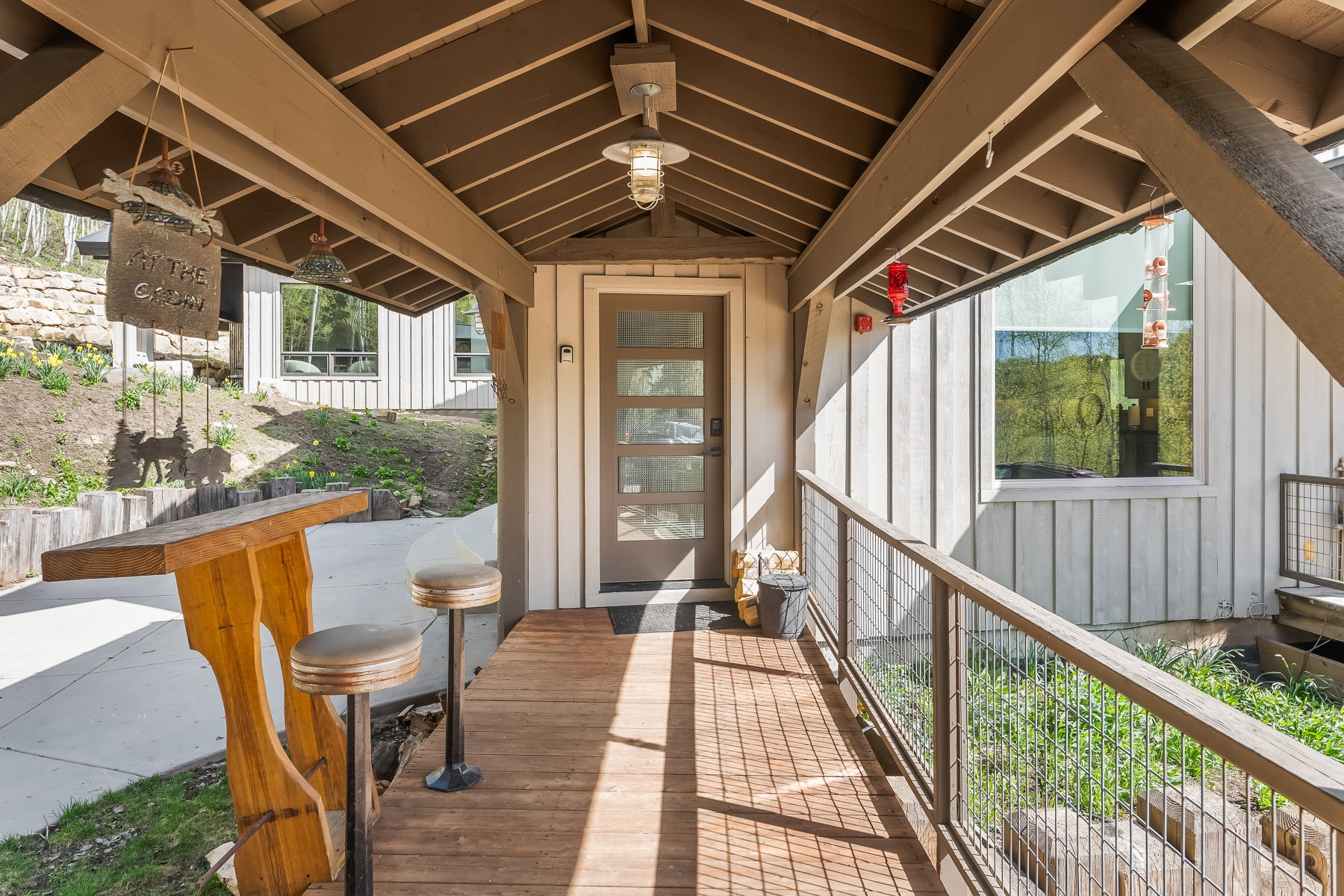 Covered outdoor walkway featuring wood-finish flooring, a contemporary entry door with frosted glass panels, and a full-light window