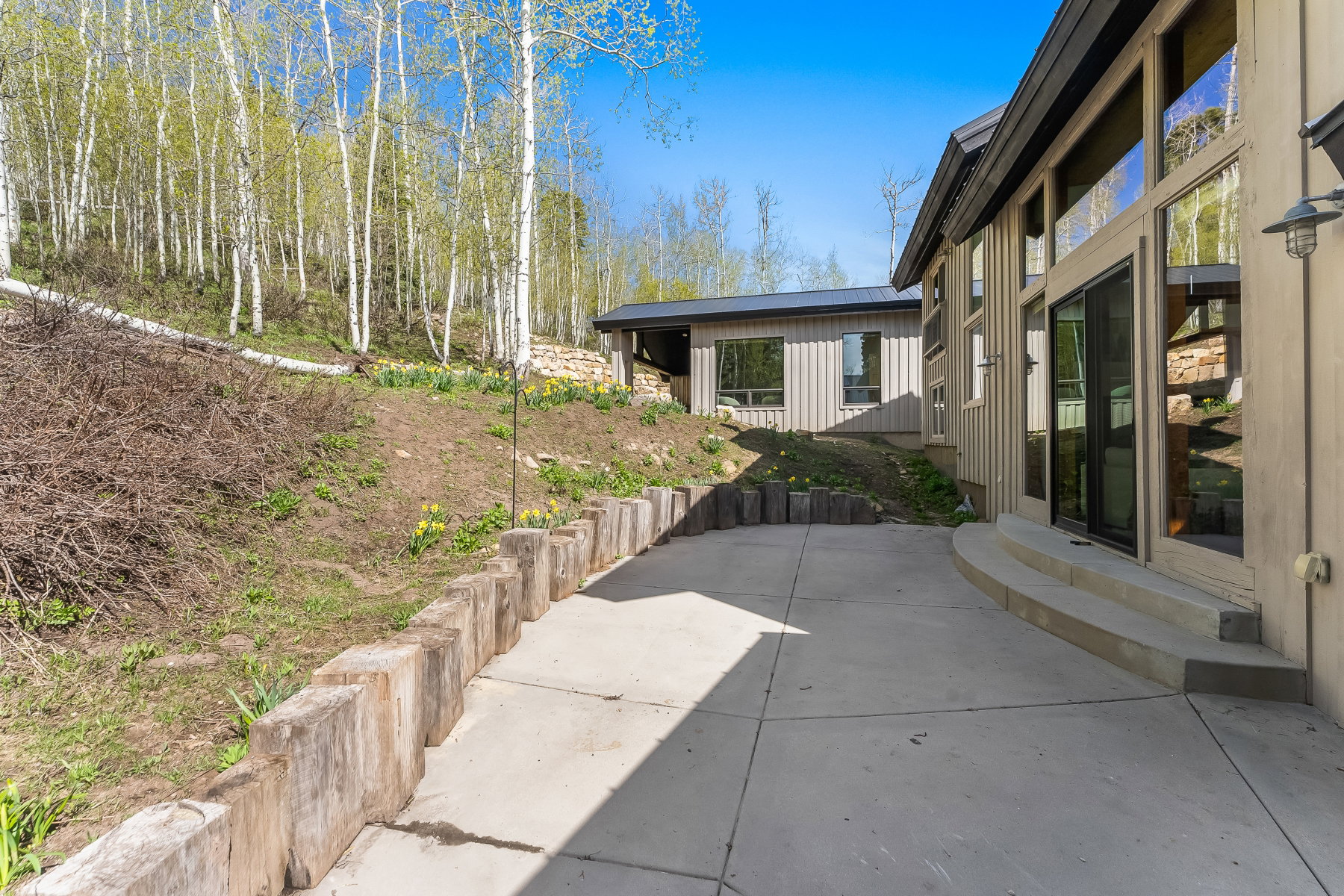 Extensive concrete patio bordered by a natural wood retaining wall