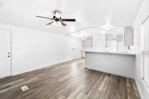 Living area featuring wood-finish flooring, white panel walls, and a ceiling fan