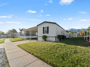 White exterior with black trim, featuring a covered carport, manicured lawn, and a concrete walkway