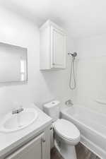 White bathroom featuring a single vanity, undermount sink, wall-mounted mirror, and white cabinetry