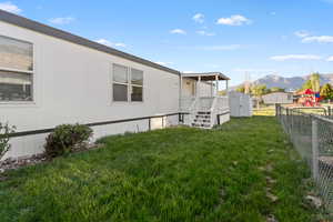 Exterior featuring white siding, multiple windows, a covered porch with stairs, and a fenced yard