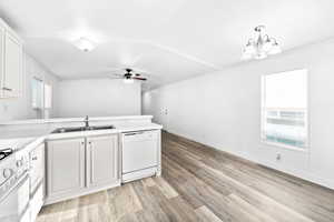 Kitchen area featuring white cabinetry, a double basin sink, and a built-in dishwasher