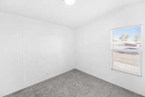 Bright room featuring white walls, gray textured carpeting, and a window with horizontal blinds