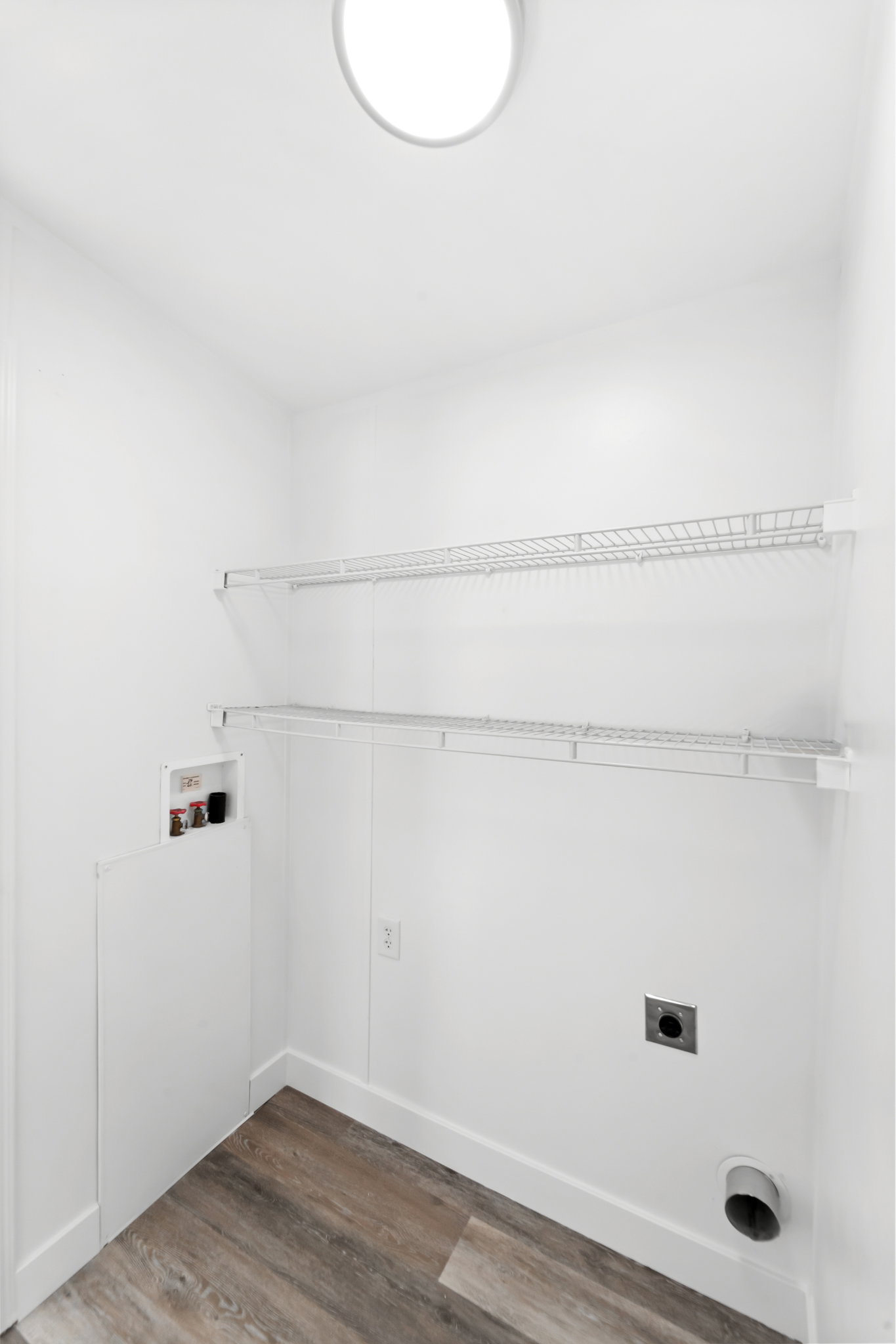 Dedicated utility space featuring wood-finish flooring, white baseboards, and bright white walls
